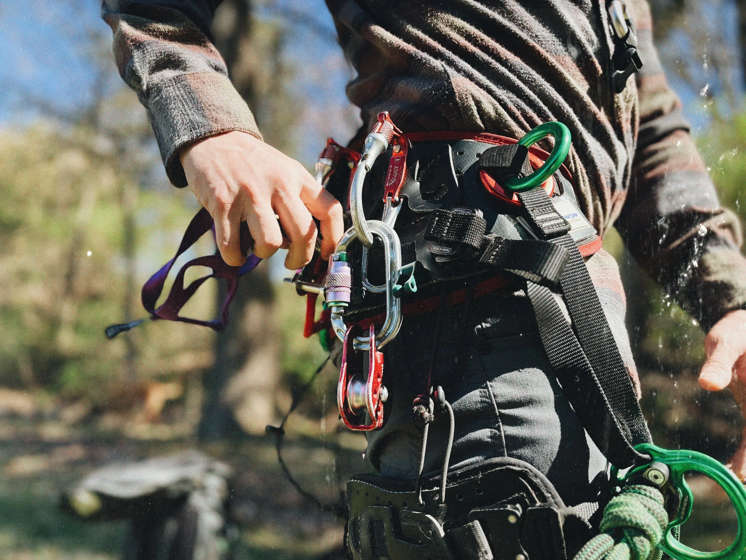 Rock climber preparing gear with carabiners and harness.
